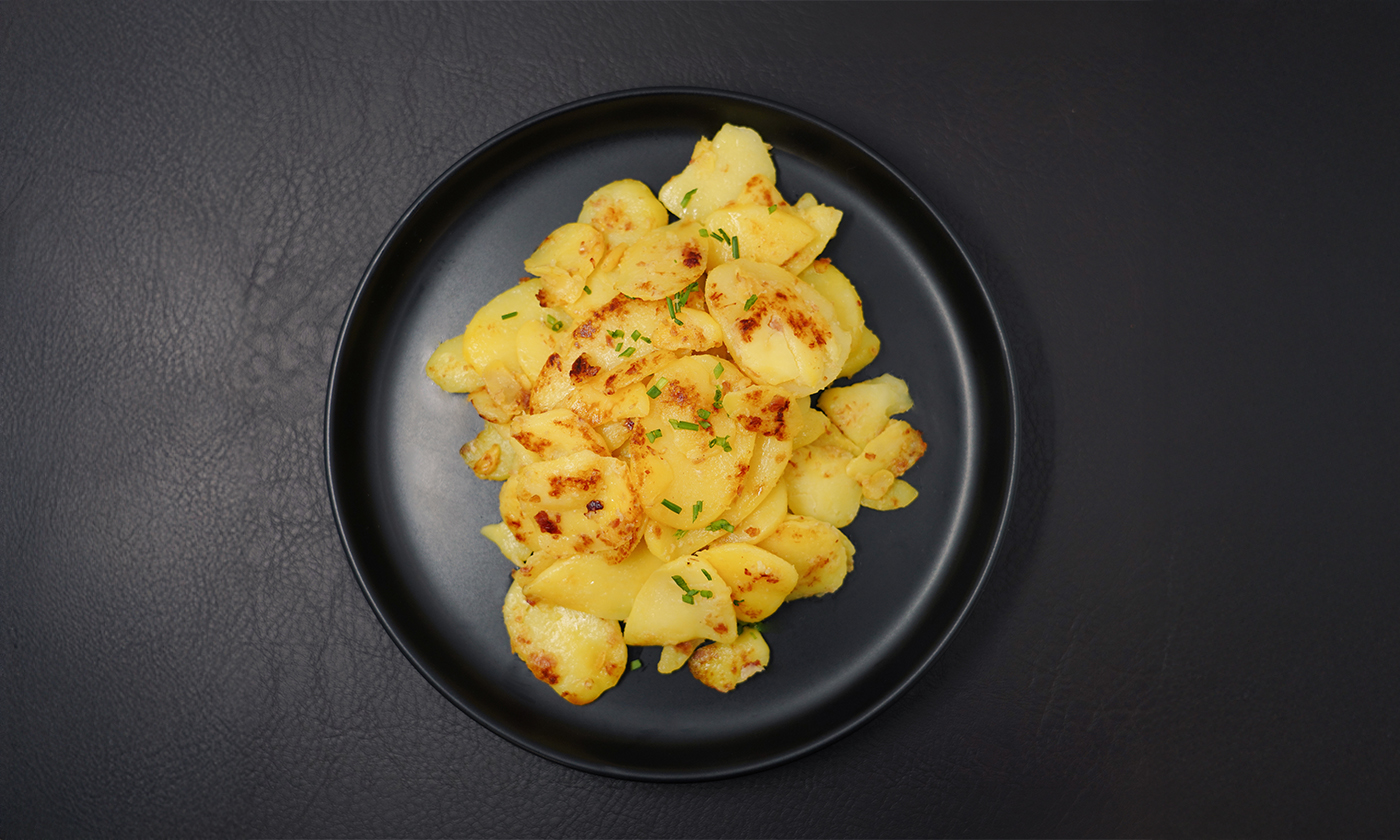 Grocholl Bratkartoffeln mit Schinken und Zwiebeln , angerichtet- Draufsicht